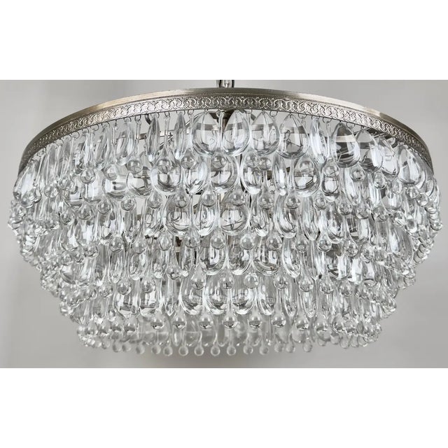A Hollywood Regency style chandelier featuring a circular cascade design that is both luxurious and timeless. The...
