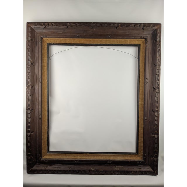 A substantial vintage Arts & Crafts style hand-carved wood picture frame, featuring a rich dark brown finish and...