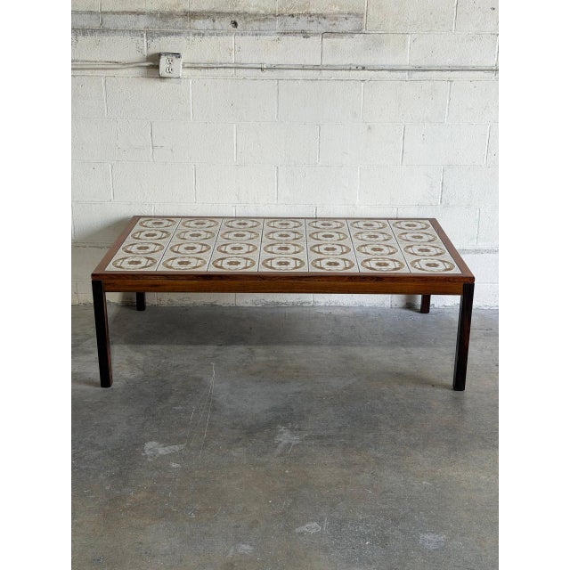 A broad rectangular frame features an inset top of glazed ceramic tiles with a starburst geometric motif. Straight square...