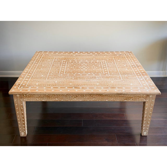 Made Goods “Tamsin” coffee table in solid teak featuring intricate hand-carved bone inlay across the top, apron, and legs....
