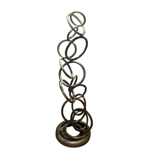 These intertwined rings of steel are finished in a dark gray enamel like coating. The rings of various sizes have been...