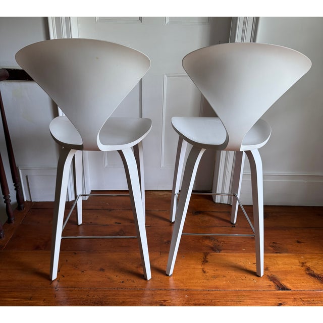A pair of Norman Cherner's iconic 1958 molded plywood stools, produced under license by The Cherner Chair Company from the...