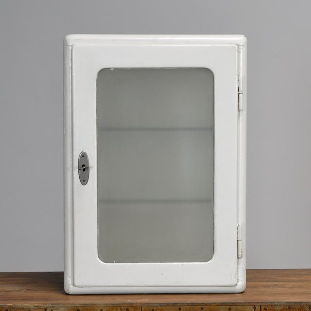 A wooden medicine cabinet from the 1930s, finished in white lacquer with a charming vintage appeal. The cabinet features a...