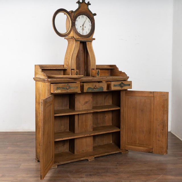 19th century Swedish pine cabinet incorporating an upper clock feature. This unique piece retains the original finish in...
