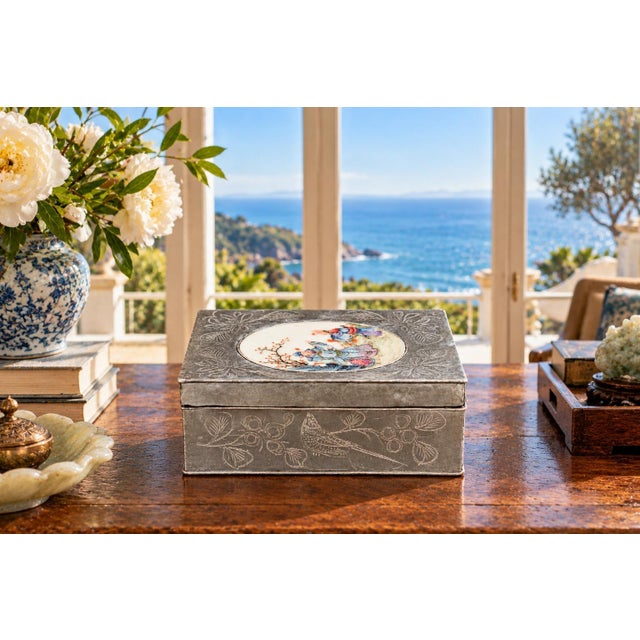 A charming Chinese export pewter box dating to the early 20th century Republic era, featuring a beautiful oval porcelain...
