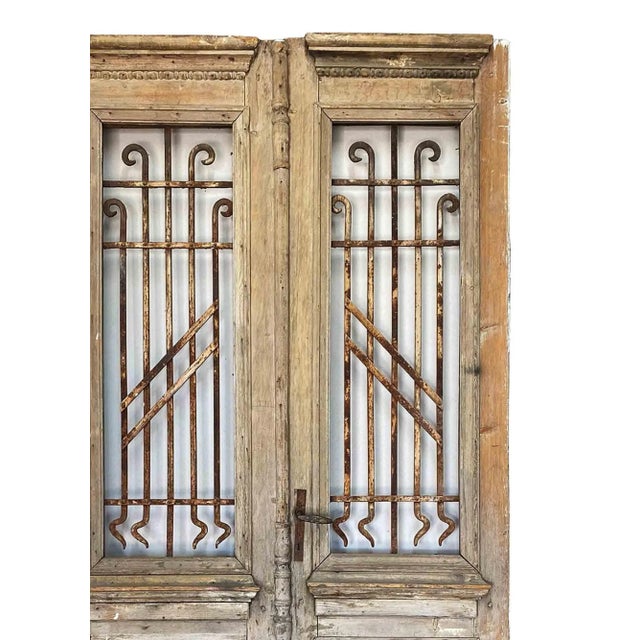 Pair of antique late 19th century rustic wooden entrance doors with wrought iron window grilles. Distressed finish...