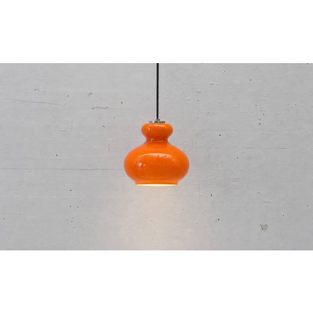 A striking vintage pendant light by peill & putzler from the 1970s. The bulbous lampshade, made of vibrant orange opal...