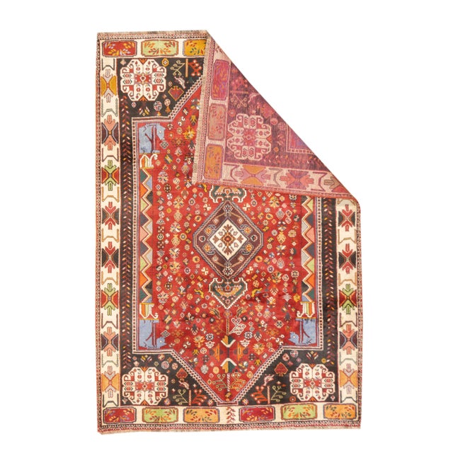 Vintage hand-knotted Persian Qashqai rug with a large stepped diamond medallion set within a field containing scattered...