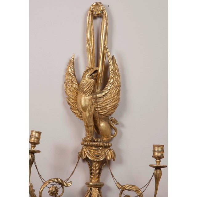 Each features a gryphon with a ring in its mouth and chains connecting to two taper candle holders, with details of leaves...