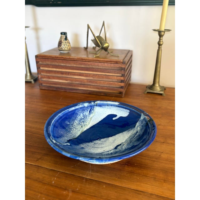 Striking vintage studio pottery bowl featuring a dramatic cobalt blue glaze with flowing white abstract forms reminiscent...