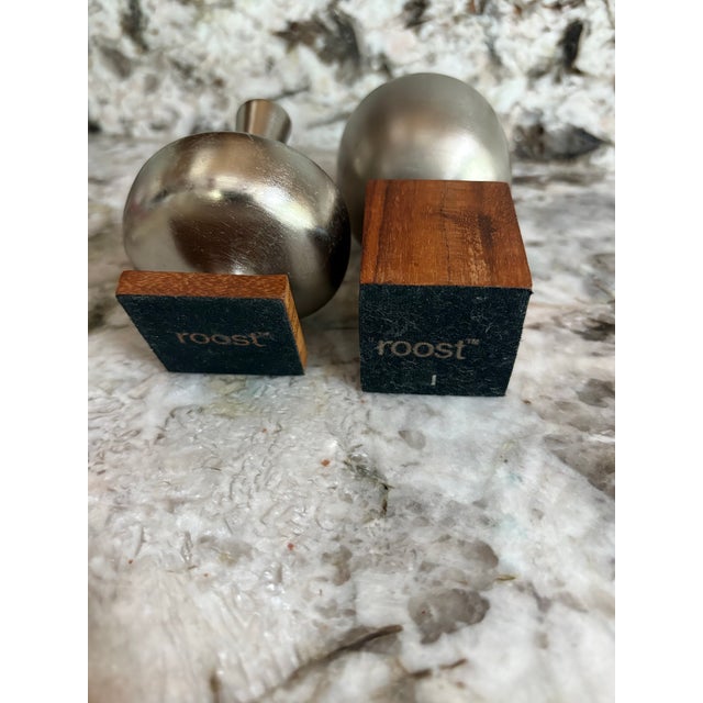 Stylish set of two Roost decorative bud vases featuring softly brushed silver-tone metal vessels mounted on warm wood...