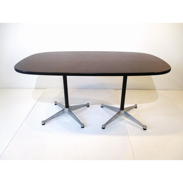 A dark walnut topped smaller scale dining table with black rubber edge trim sitting on double pedestal star base ....