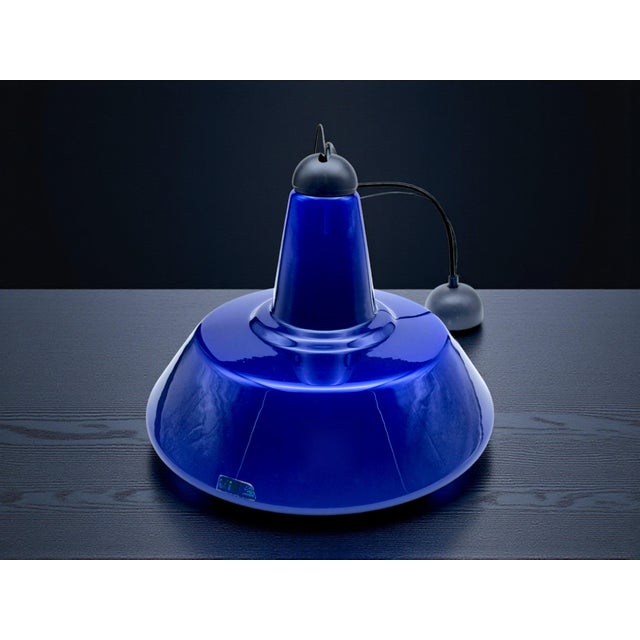 Pendant lamp with an industrial and modern design, featuring a murano glass shade with a deep blue exterior and white...