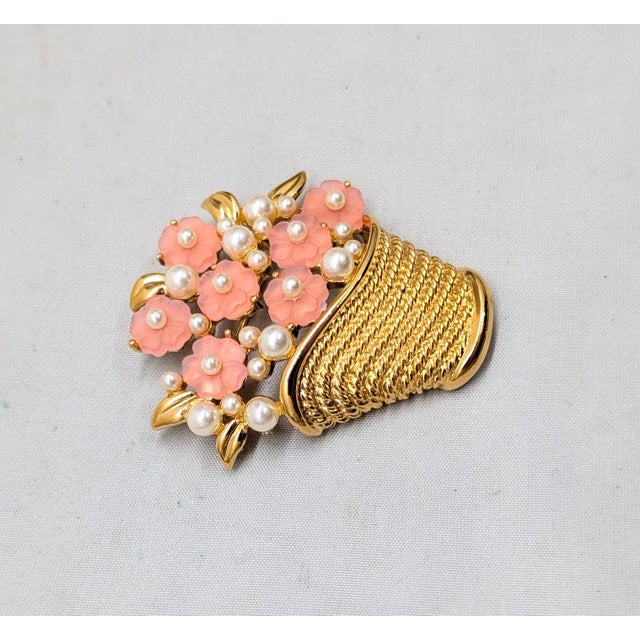 1980s goldtone molded pink resin flowers with faux-pearl centers and accents in a basket brooch with a security clasp....