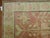 One of a kind Khotan rug with a soft pink field consisting of a flower vase motif and a soft green border.