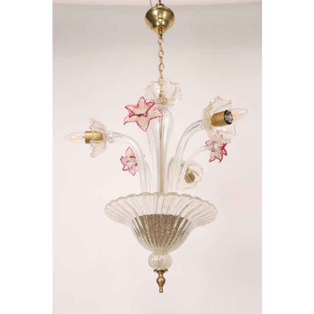 This three-arm Murano style glass chandelier features clear glass infused with fine gold leaf throughout. The design is...