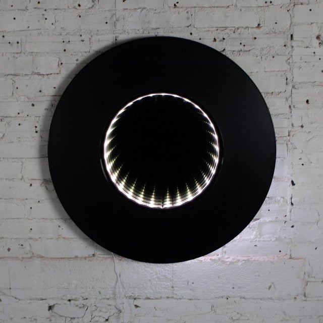 Fabulous vintage Modern to Postmodern infinity vortex wall mirror composed of a round black laminate frame, smoky toned...
