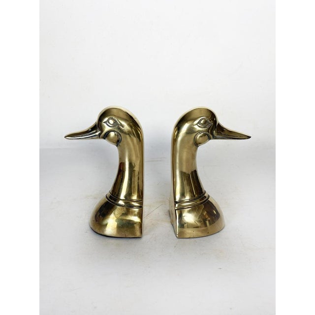 Pair of gilt brass bookends, France, 1970s, depicting stylized duck heads. Each piece has an elegant, sculptural form,...