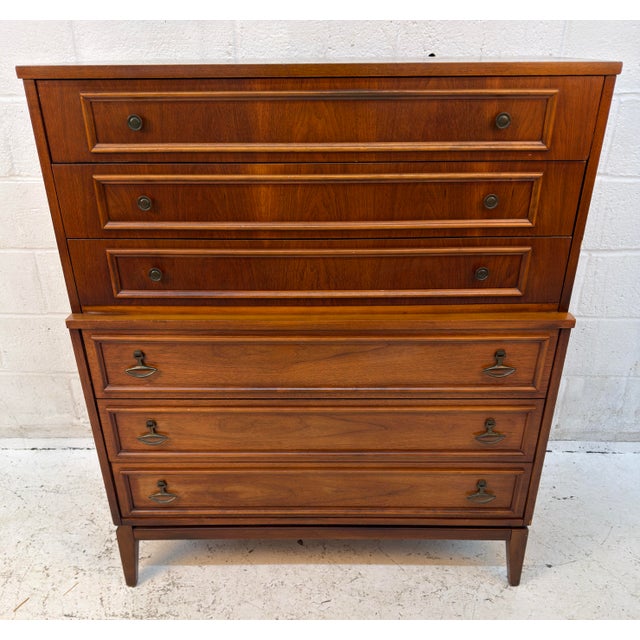 Striking Mid-Century Modern highboy dresser featuring a warm walnut finish, rich wood grain, and beautifully detailed...