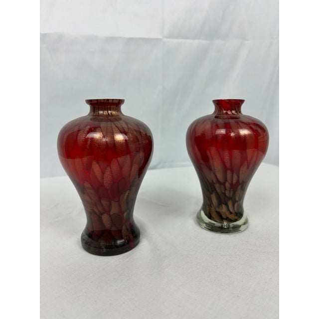 A refined pair of 1970s Murano glass vases, handblown in rich red glass with shimmering goldstone inclusions that catch...
