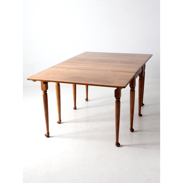 This antique wood drop-leaf table combines space-saving design with a generous dining surface. With hinged drop leaves and...