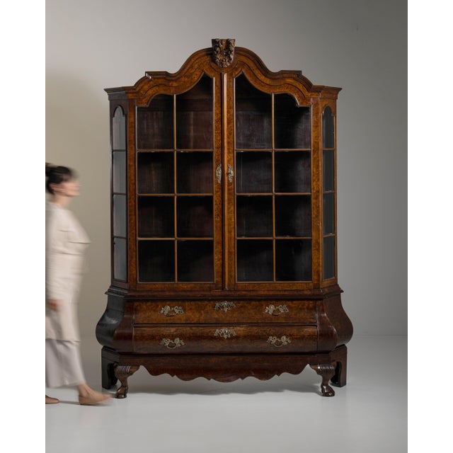 This 19th century Dutch vitrine with brass hardware from Netherlands is built in dark wood as a tall, glazed display...