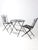 A mid-century wrought iron patio set in the style of classic French bistro seating, featuring graceful scrollwork backs...