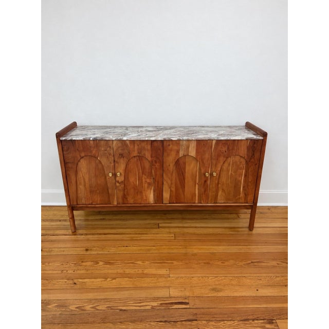 Cathedral Sideboard constructed in acacia wood featuring a marble top and brushed brass knobs. Interior with shelving (see...