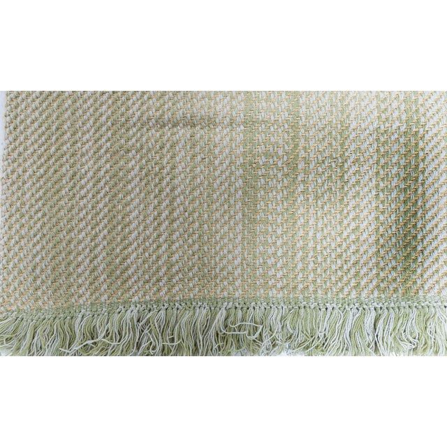 This contemporary flat-weave wool rug showcases a subtle striped composition rendered in a soothing palette of soft sage...