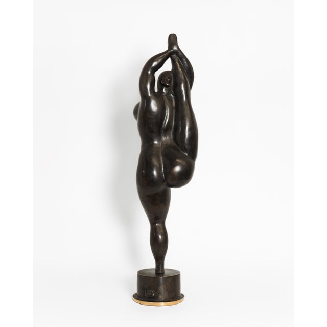 A contemporary figurative bronze of a woman standing on the toes of one foot, her other leg drawn straight up beside her...