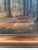 This signed antique original landscape oil painting, from around 1910, shows a forest landscape with a narrow stream...
