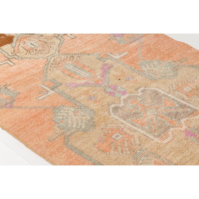 This is a vintage Turkish Oushak rug from the Mid 20th Century. The piece was hand-knotted.