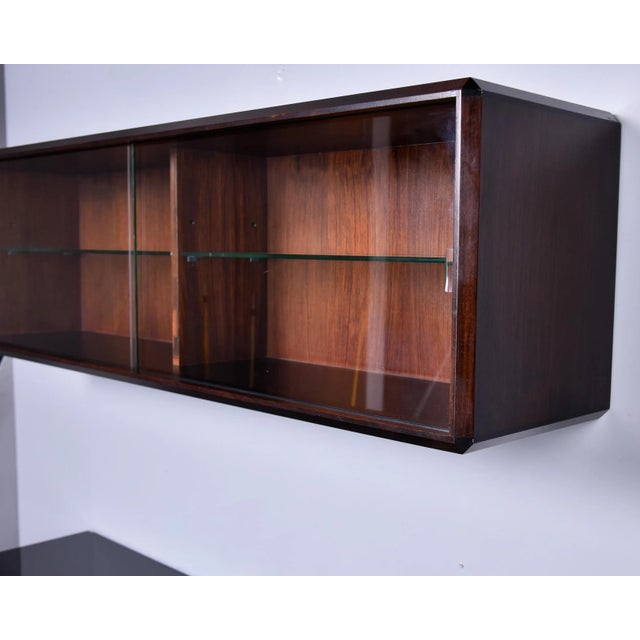 Found in Italy, this wall-mounted cabinet dates from the 1960s. Cabinet has a walnut base with sliding clear glass doors...