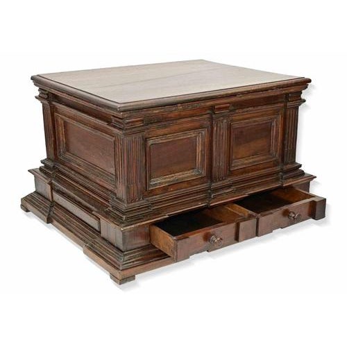 A robust and characterful wooden coffer of rectangular form, raised on a molded plinth base with shaped apron. The façade...