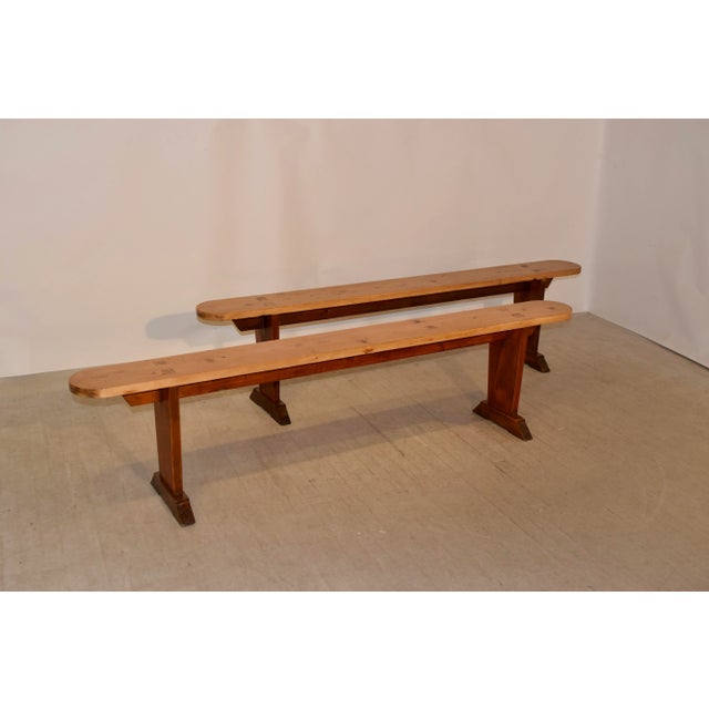 Pair of 19th century pine benches from France with plank seats with rounded ends and pegged construction following down to...