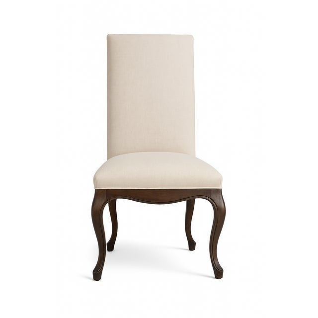 Pair of official Restoration Hardware side chairs featuring sculpted dark walnut legs and crisp white linen upholstery....