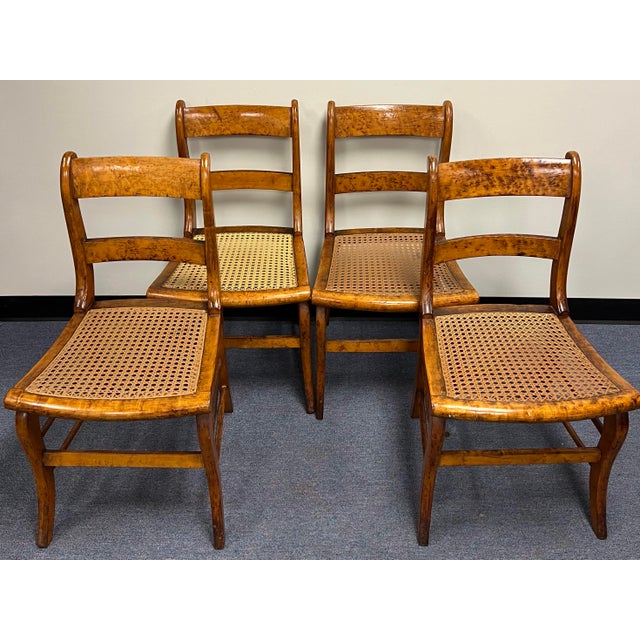 Striking set of four solid Birds Eye maple American classical or Federal style cane seat dining chairs. The chairs feature...