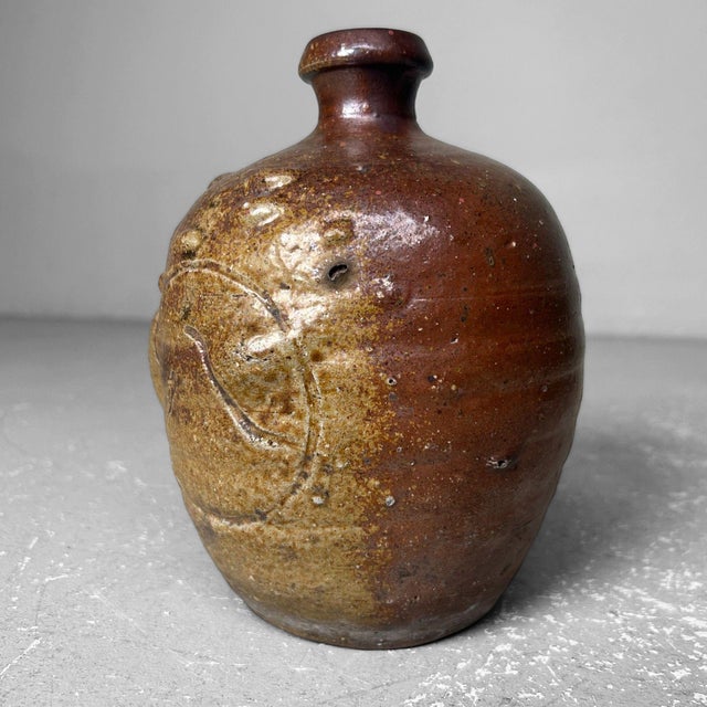 This earthenware jug from the Taishō period is a stunning example of traditional Japanese craftsmanship from Nagoya....