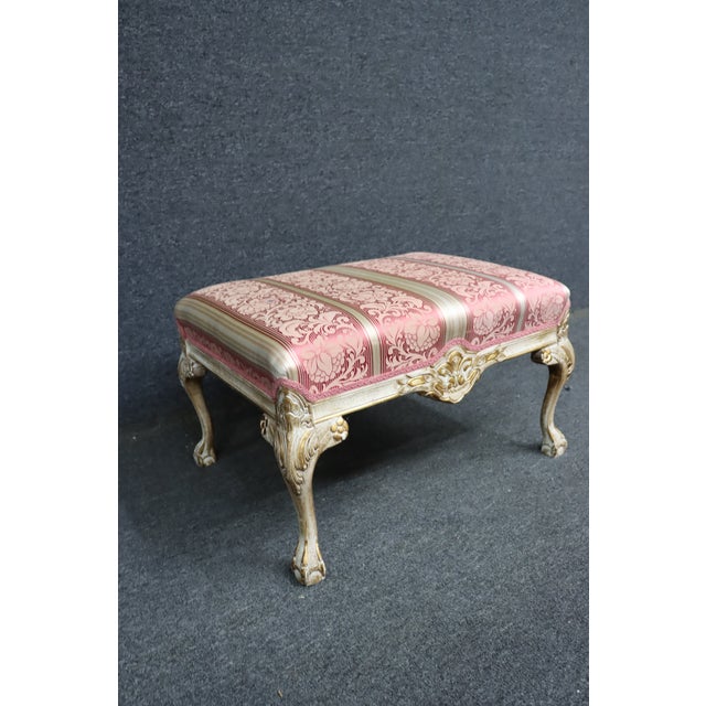 Louis XV style footstool featuring a carved and painted frame with claw and ball feet, floral carvings, and a generously...
