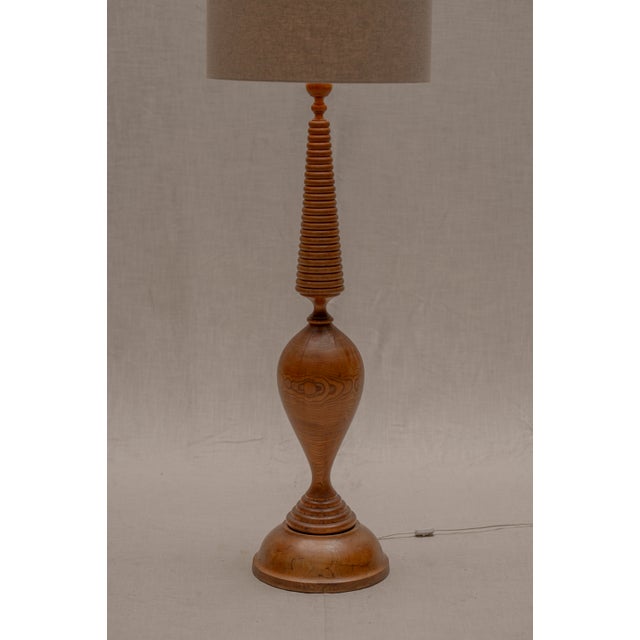 Elegant and sculptural French mid-century floor lamp from the 1960s, handcrafted from a single solid piece of turned wood....