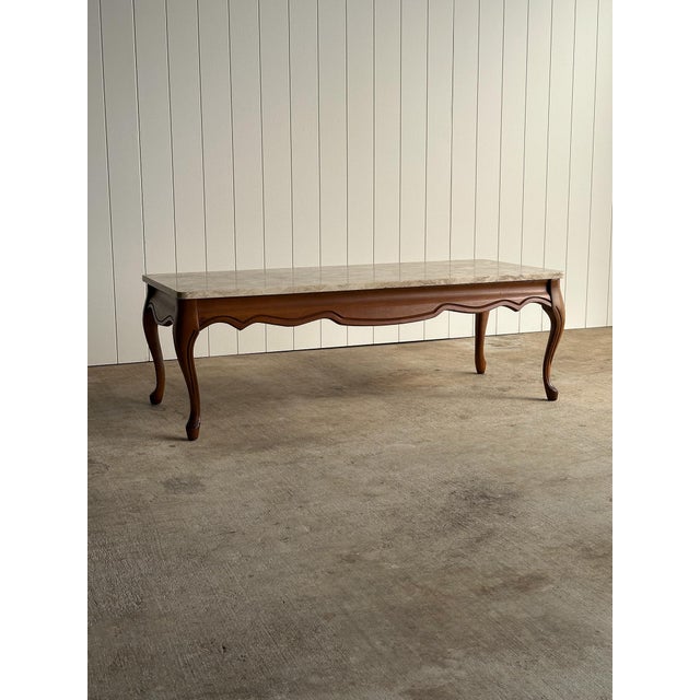 Vintage coffee table with marble top, serpentine apron, and carved cabriole legs. Warm wood tone with subtle carved...