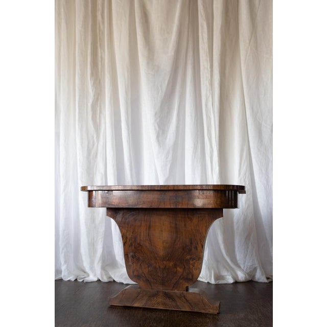 This striking pair of 1930s French Art Deco demilune tables showcases dramatic wood grain with a rich, warm finish. The...