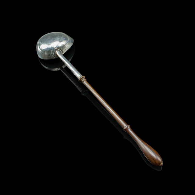 This is an antique toddy ladle. An English, silver and mahogany long serving spoon, dating to the Georgian period,...