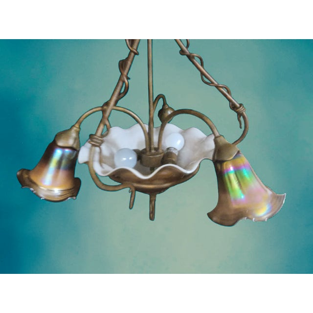 A stunning Art Nouveau–inspired iridescent glass chandelier paired with three matching signed sconces, designed by Todd...