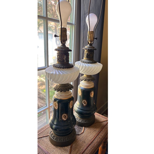 A striking pair of mid-century table lamps converted from oil lamp originals, each featuring a deep hunter green ceramic...