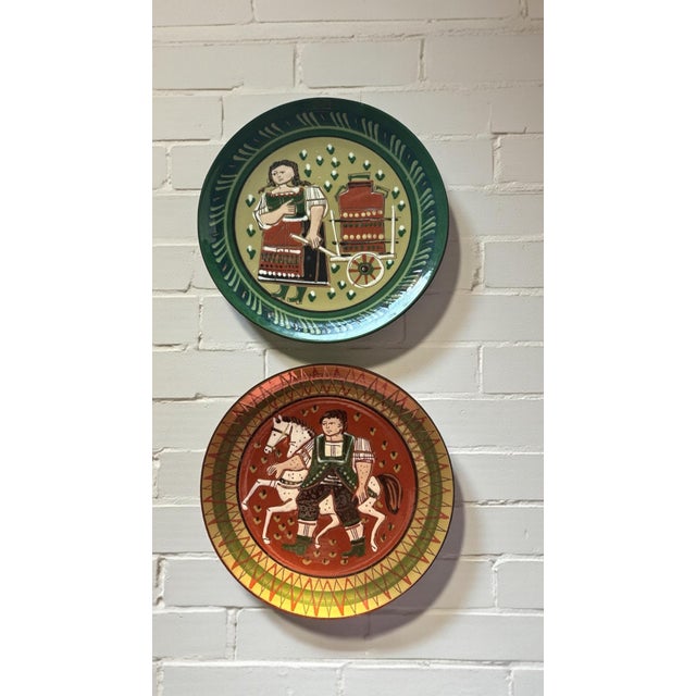This pair of mid-century Swiss folk art wall plates is attributed to Heimatwerk Basel, a renowned workshop known for...