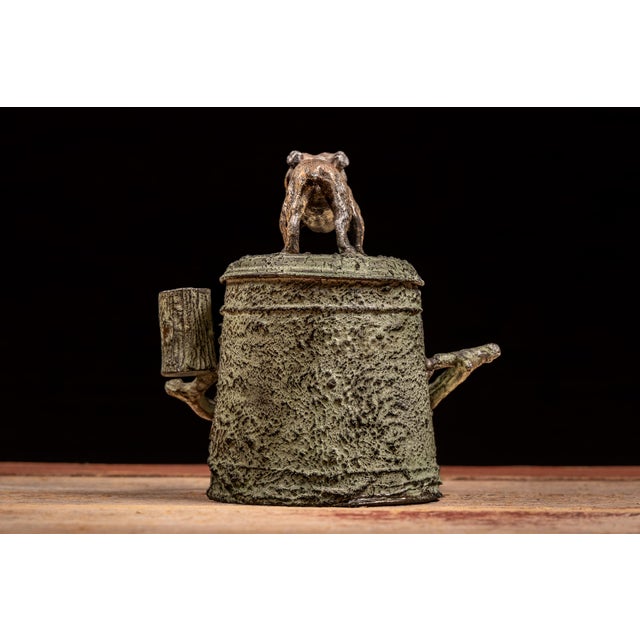 An antique cast-metal desk humidor modeled as a naturalistic hollow tree stump. The cylindrical body is covered with...