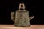 An antique cast-metal desk humidor modeled as a naturalistic hollow tree stump. The cylindrical body is covered with...