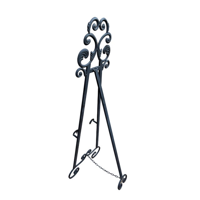 Elegant vintage wrought iron floor easel featuring ornate scrollwork and a matte black finish. The graceful, hand-forged...