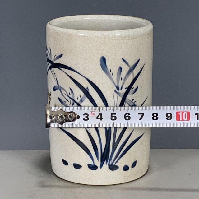 A charming Chinese blue and white porcelain brush pot (bitong). The cylindrical vessel features a creamy, all-over crackle...